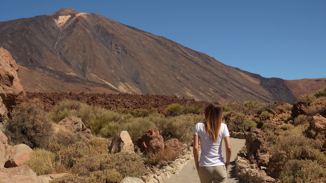 Tourist walking on a path in Teide National Park, Tenerife, Canary Islands, Spain