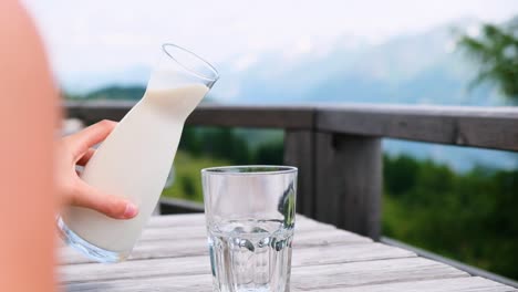 pouring milk into glass in the alps on a mountain, fresh from the cows location: south tyrol, italy