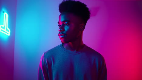 young man in vibrant neon-lit room with glowing sign