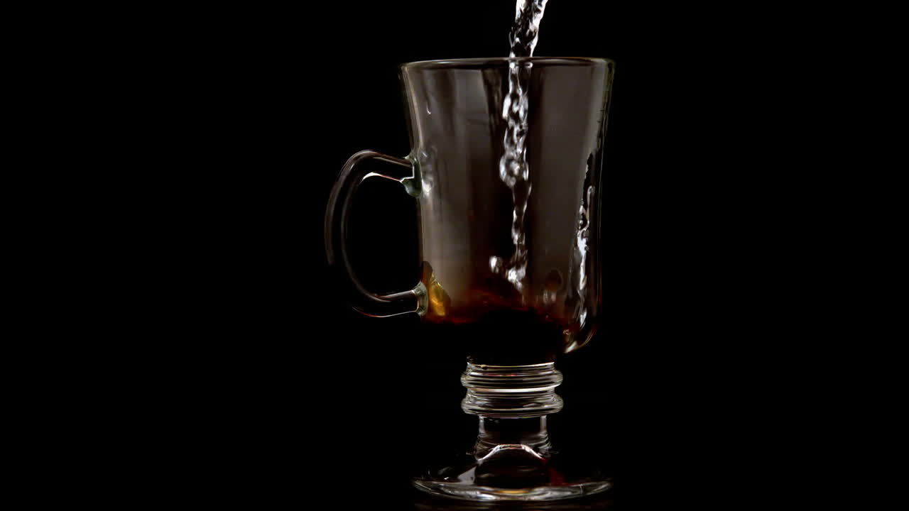 Hot water pouring over coffee granules in a glass
