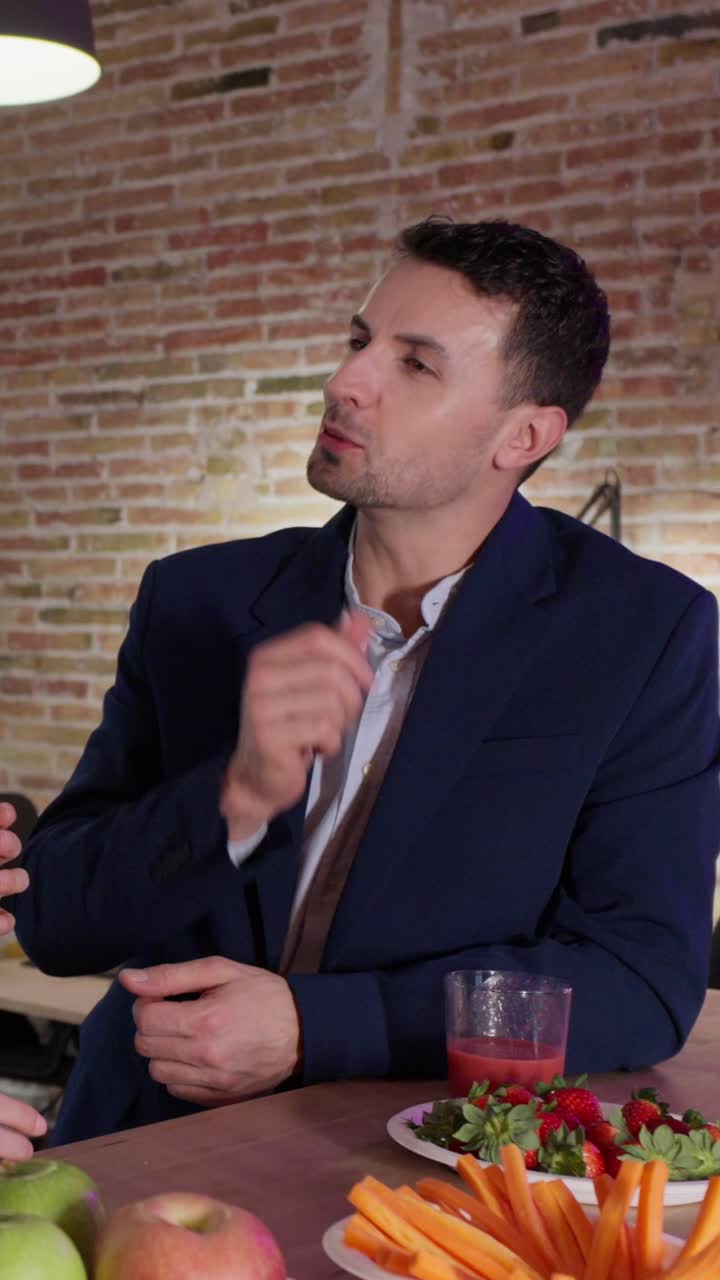 A man in a suit at a table with food and drink