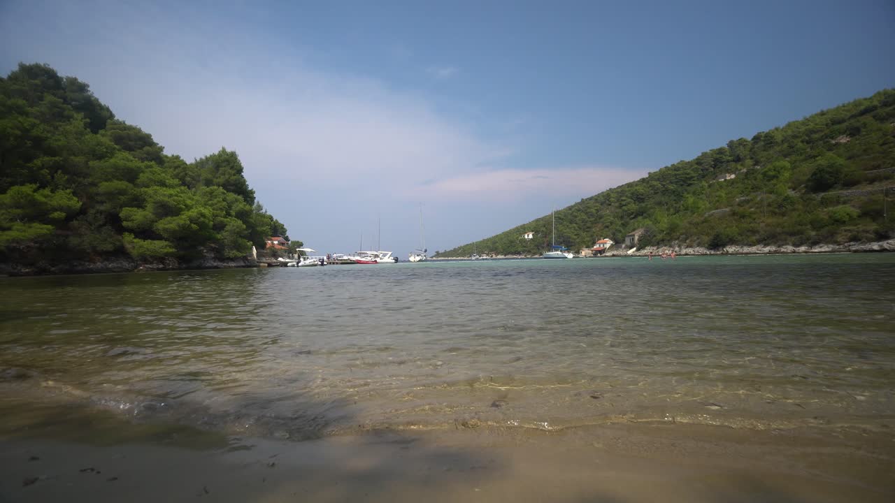 크로아티아의 아름다운 섬 석호에 있는 모래 해변으로 씻겨나가는 맑고 따뜻한 물의 낮은 각도