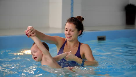 un bebé lindo disfrutando con su madre en la piscina.