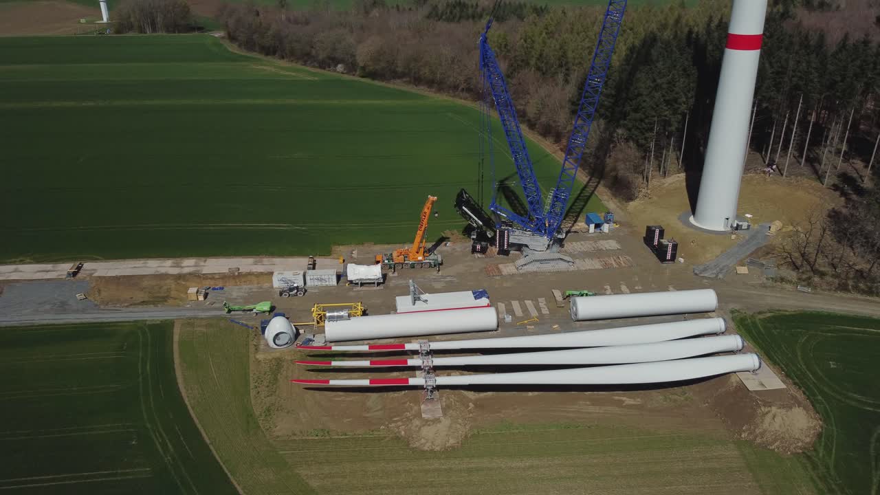 sitio de construcción de una turbina eólica con partes de molino de viento en el suelo - toma aérea