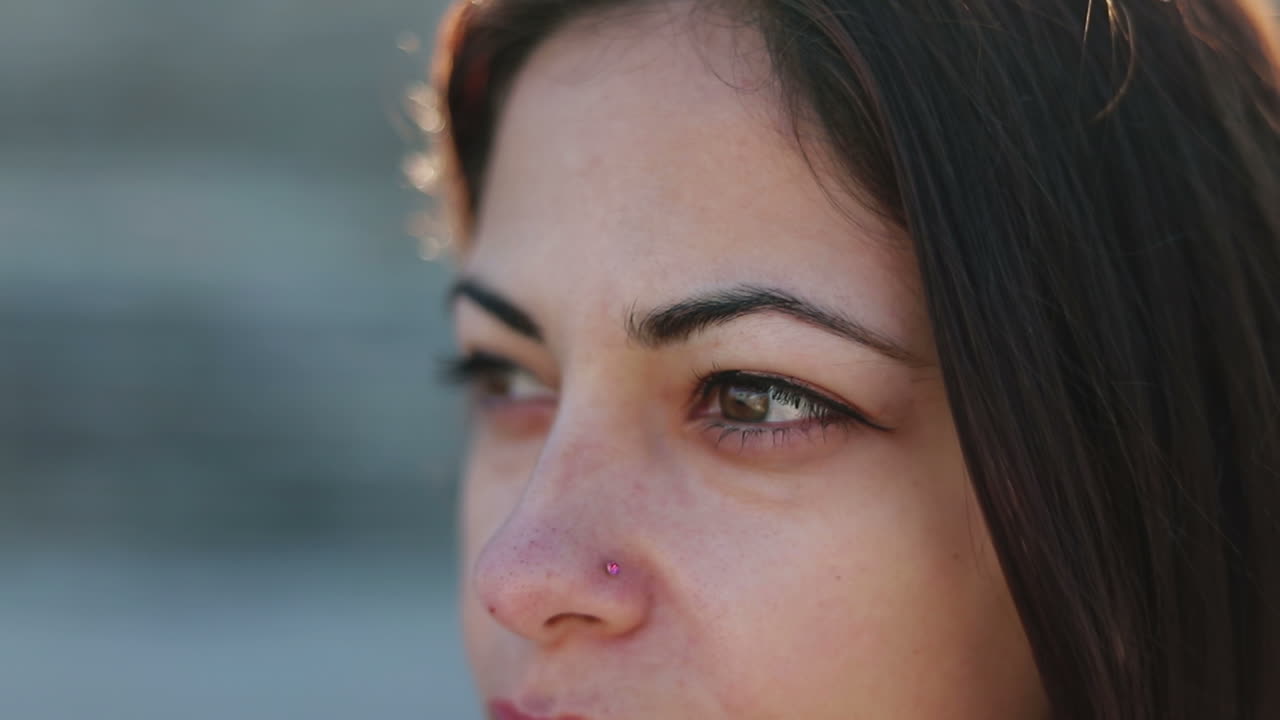 hermosa joven morena con piercing mirando a un lado