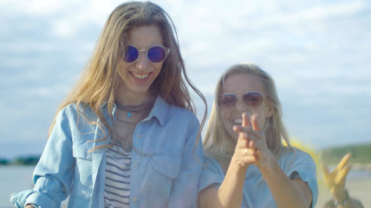 две красивые счастливые девушки смеются и празднуют праздник холи, бросая красочный порошок в воздух.