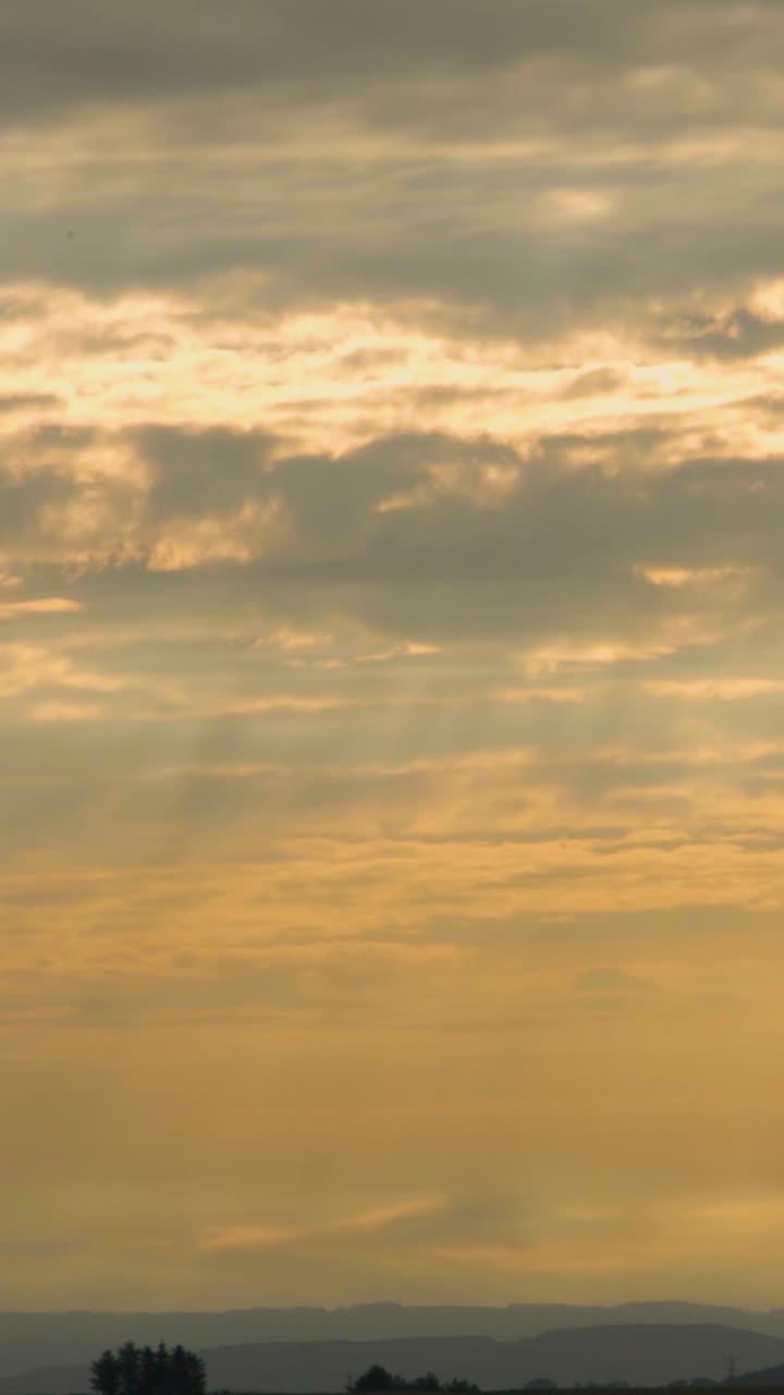 Vertical Video Early Morning Timelapse with Layers of Clouds Moving Over Landscape. Light Rays Piercing Through Creating Ethereal Tone.