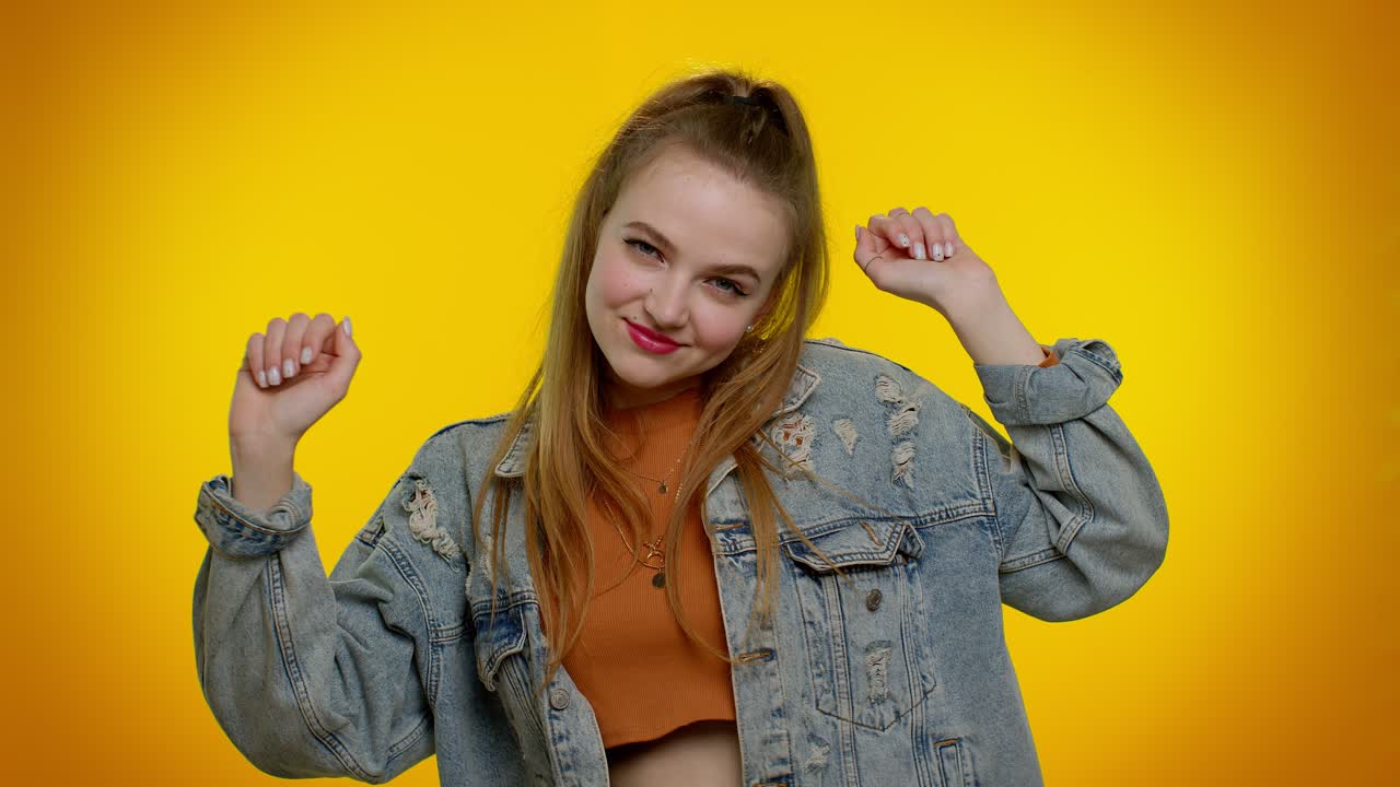 Ragazza alla moda e allegra che balla e si muove a ritmo, facendo dab alzando le mani, eseguendo il gesto del dubdance.
