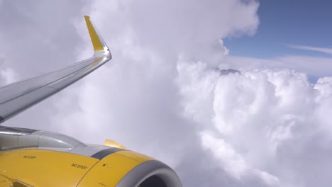 airplane wing and engine in flight as seen from passenger window over clouds