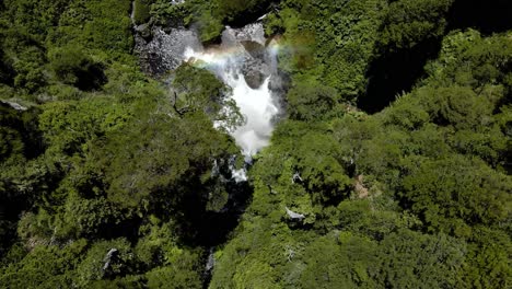 Descenso-Aéreo-En-La-Cascada-Salto-El-Leon-Con-Niebla-Y-Arco-Iris-Rodeado-De-Bosque-Verde-Y-Denso,-Pucon,-Chile