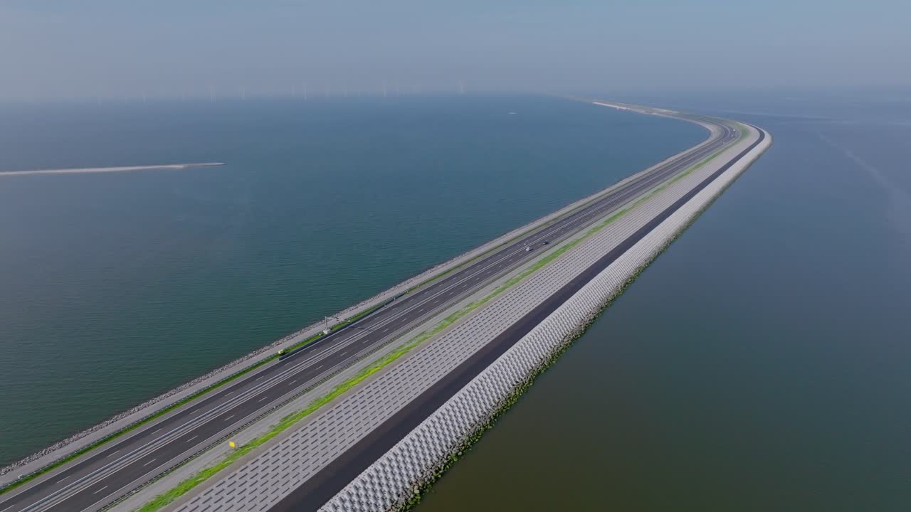 Drone pan left showing the Afsluitdijk highway cutting through calm sea waters connecting two Dutch provinces