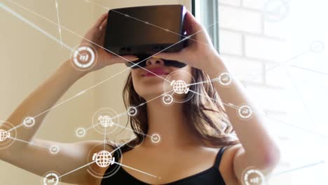 Animation-of-network-of-connections-with-icons-over-woman-wearing-vr-headset