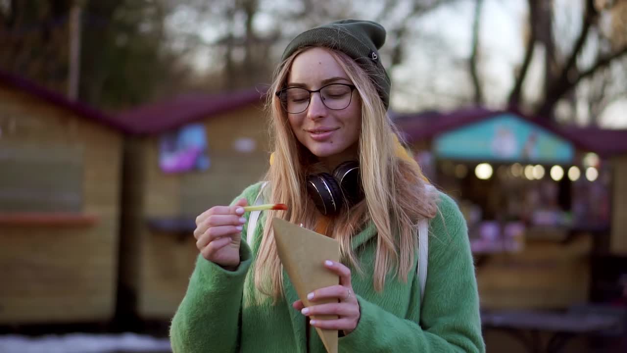 mujer comiendo papas fritas al aire libre en la feria callejera de invierno