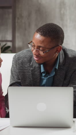 african-american english native speaker tutor gives task to brother and younger sister students at laptop computer in living room slow motion