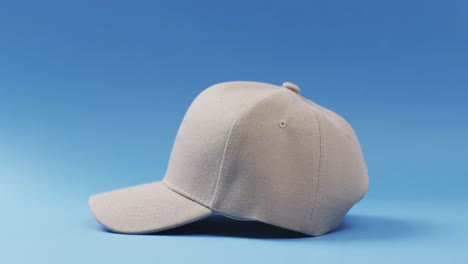 Video-of-beige-baseball-cap-and-copy-space-on-blue-background