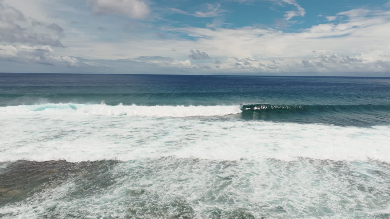 Perfect A frame wave crashes and breaks over fringing reef in the South Pacific, Rarotonga Cook Islands, drone tracking left
