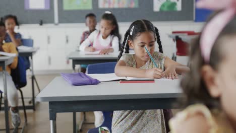 Focused-diverse-schoolchildren-writing-at-desks-in-elementary-school-classroom,-slow-motion