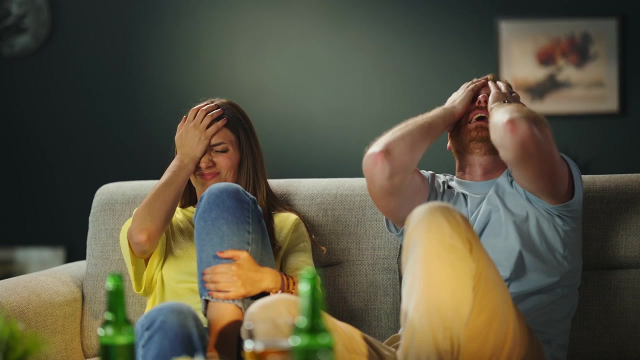 Coppia che guarda una partita sportiva in TV e reagisce con delusione