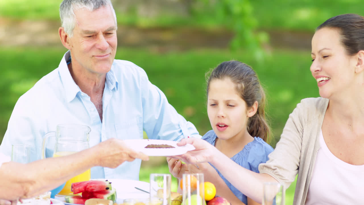 아버지는 바베큐에서 가족에게 햄버거를 제공합니다.