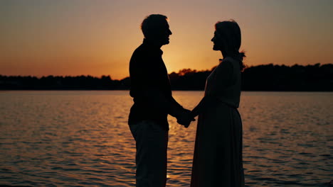 senior couple holding hands at sunset by the lake