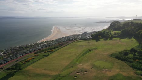 imágenes aéreas de un paso elevado panorámico desde el campo de golf hasta la costa del estuario del cuarto en escocia