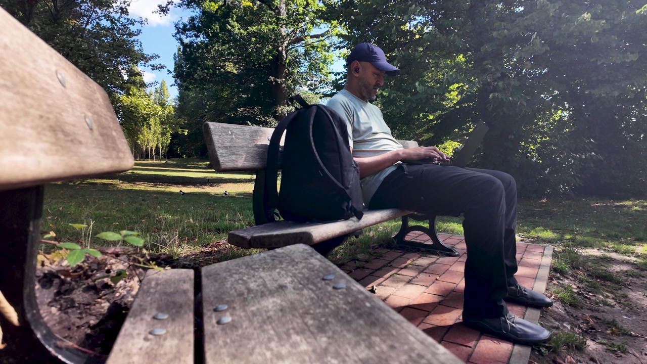 South asian freelancer working remotely on laptop in a park, enjoying the fresh air and sunlight