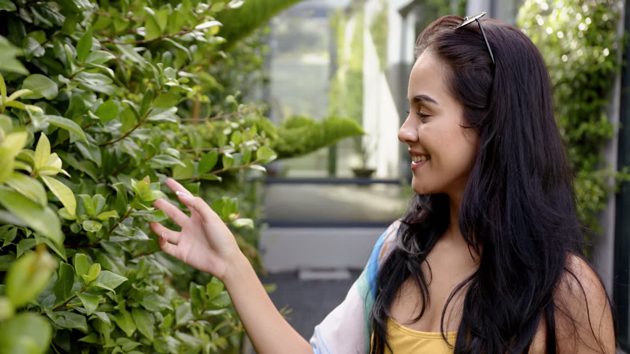 인종 여성이 집 뒷마당의 정원에서 초록색을 감상합니다.