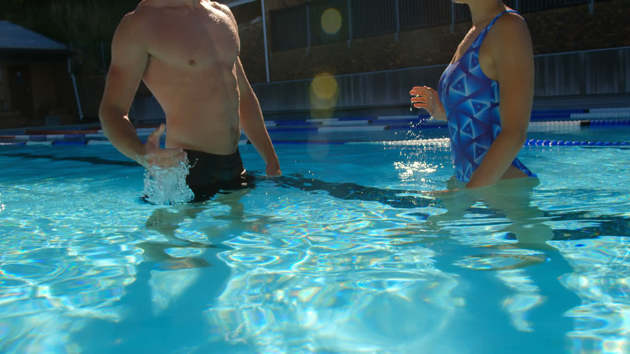 pareja dando cinco en la piscina 4k