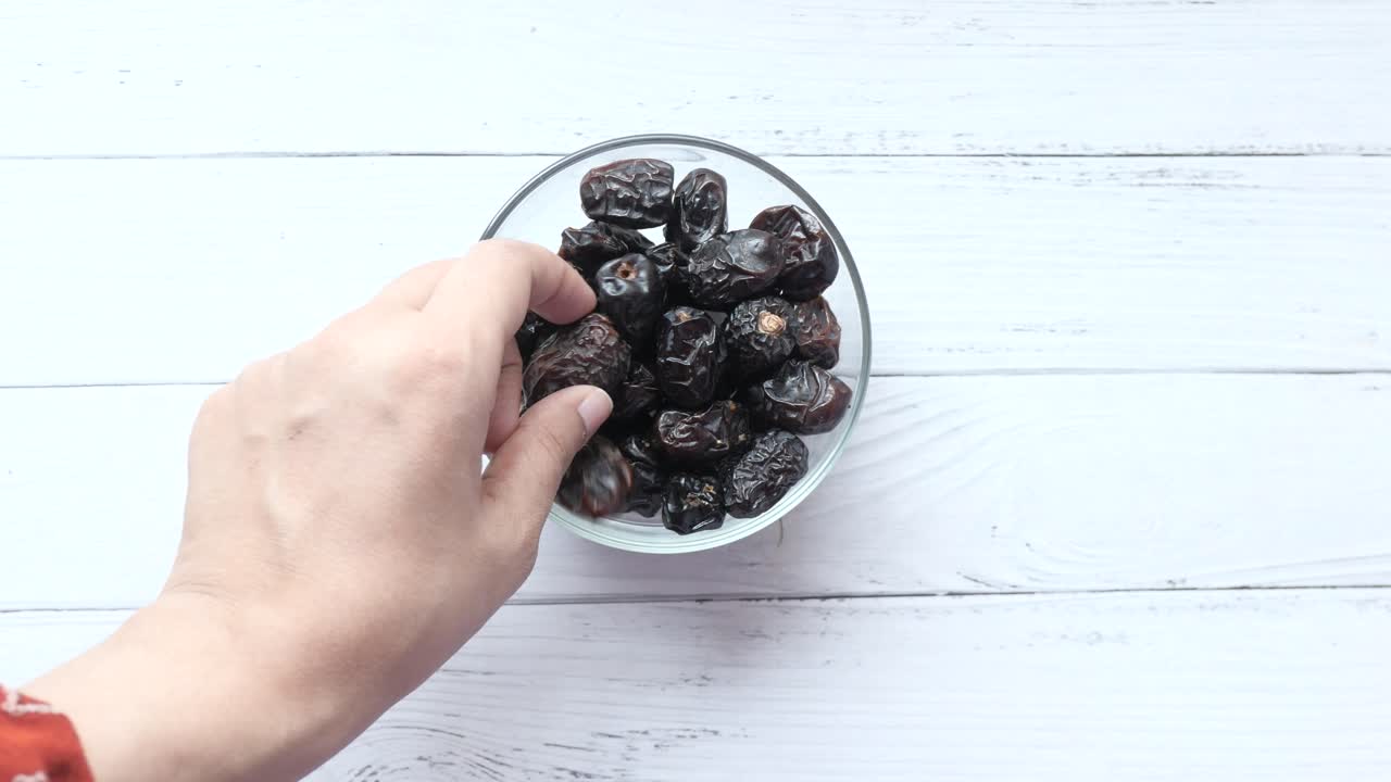 Dried Dates in a Glass Bowl on a White Wooden Table