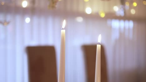 two lit white candles on a table