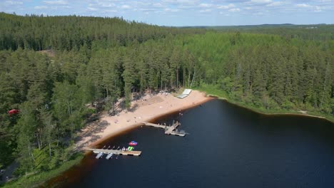 drone descends above people playing swimming relaxing by alpine lake dock and cabin