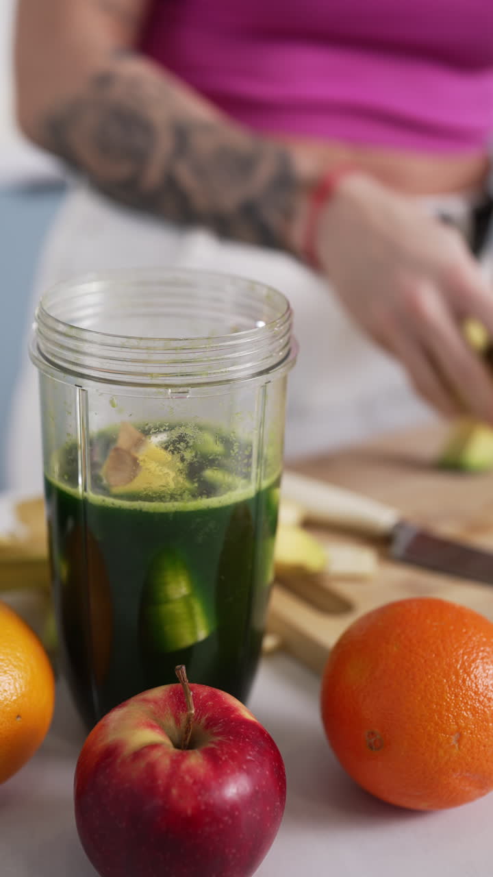 Vertical - Tattooed Woman Preparing Smoothie With Fresh Chopped Fruits In Kitchen. closeup shot