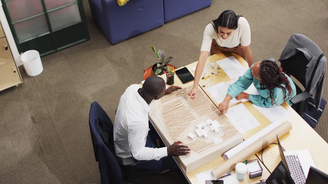 Happy diverse architects looking at architectural models at office