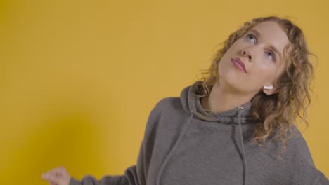 foto de estudio de una joven escuchando música en el teléfono móvil y bailando con fondo amarillo 1