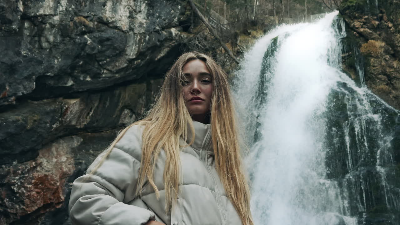 Woman standing in front of a waterfall in a forest