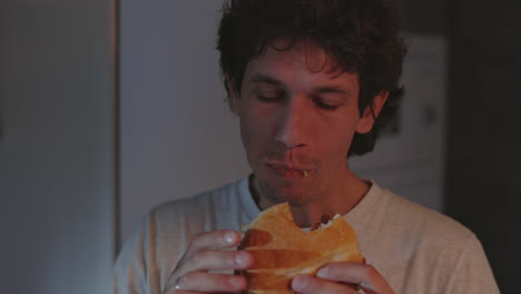 man eating a burger or sandwich late at night