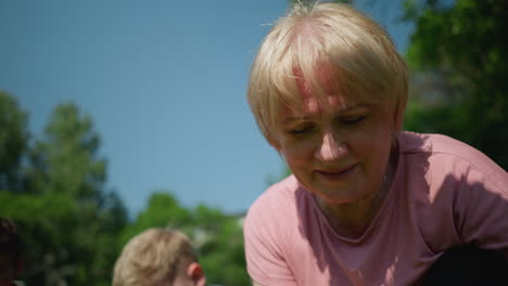 close-up of a woman smiling and focused on her task, with the shadow of someone cast upon her, a young boy s head is visible nearby