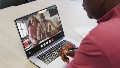 Afroamerikanischer-Mann-Nutzt-Laptop-Für-Videoanrufe,-Mit-Verschiedenen-Geschäftskollegen-Auf-Dem-Bildschirm