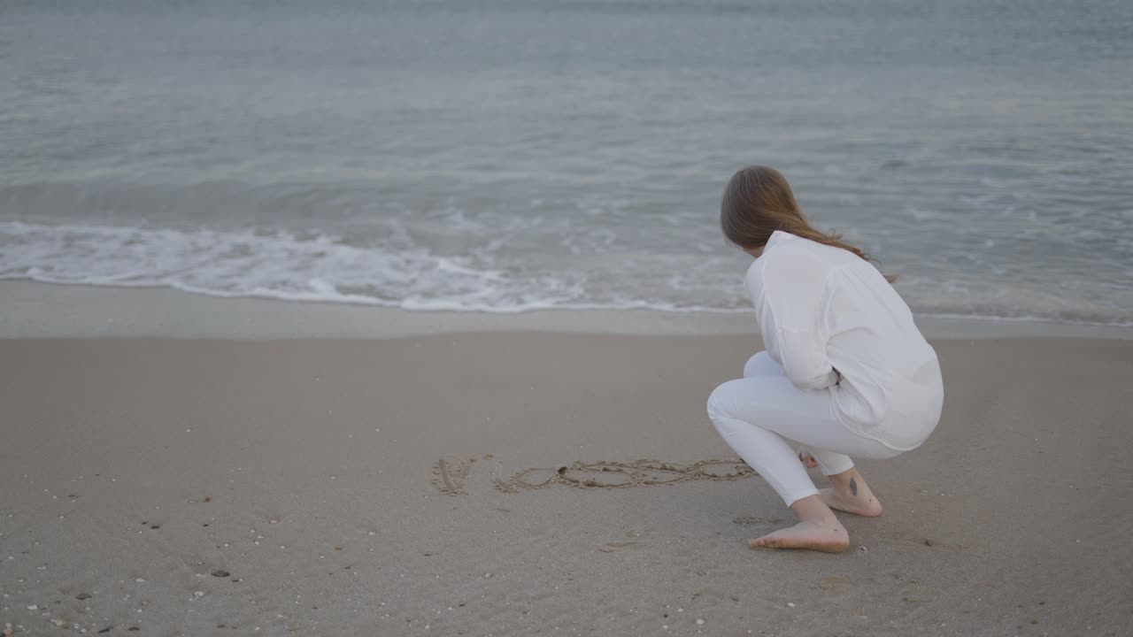 Woman Writing in the Sand on the Beach