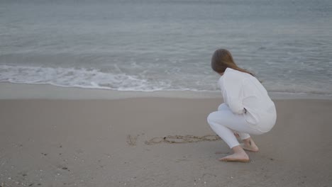 woman writing in the sand on the beach