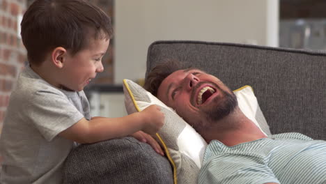 padre e hijo divirtiéndose jugando en el sofá juntos