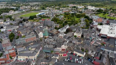 Toma-Aérea-Descendente-De-Edificios-En-El-Centro-De-La-Ciudad.-Casas-A-Lo-Largo-De-Calles-Estrechas-Y-Plazas.-Ennis,-Irlanda