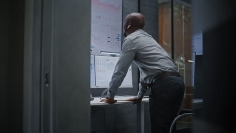 financial analyst suffering from financial crisis, yelling in phone, analyzing exchange market charts in office. african american businessman furious about stock market collapse. vertical shot.