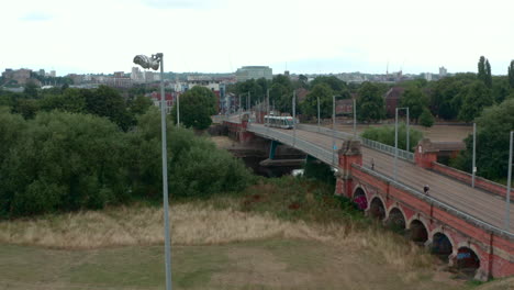Descending-drone-shot-of-Nottingham-tram-over-river-Trent-Wilford-toll-bridge