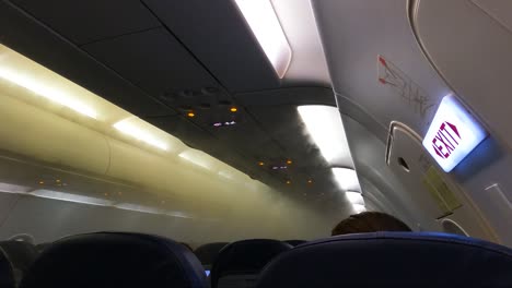 fog filling airplane cabin, coming out from airconditioning vents due to hot and humid outside air condensing. - pov