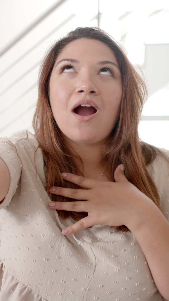 Vertical video of happy plus size biracial woman having video call, talking, slow motion