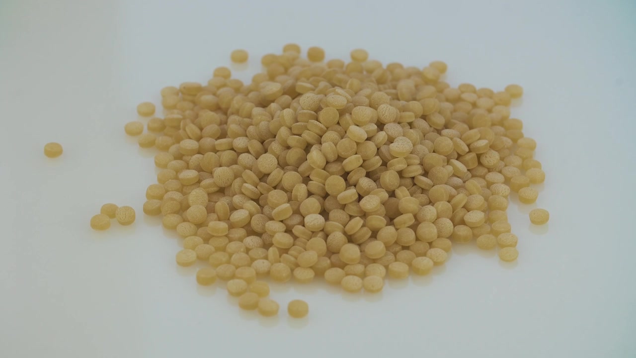 Haug med små runde pastakorn eller couscous på hvit bakgrunn
