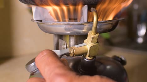 la mano enciende la estufa de campamento de queroseno, manipula la perilla de encendido para encender la llama, cerrar