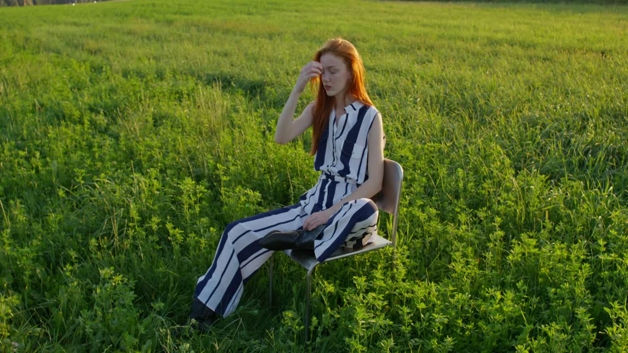 해가 지는 동안 에 앉아 있는 줄무 스을 입은 여자