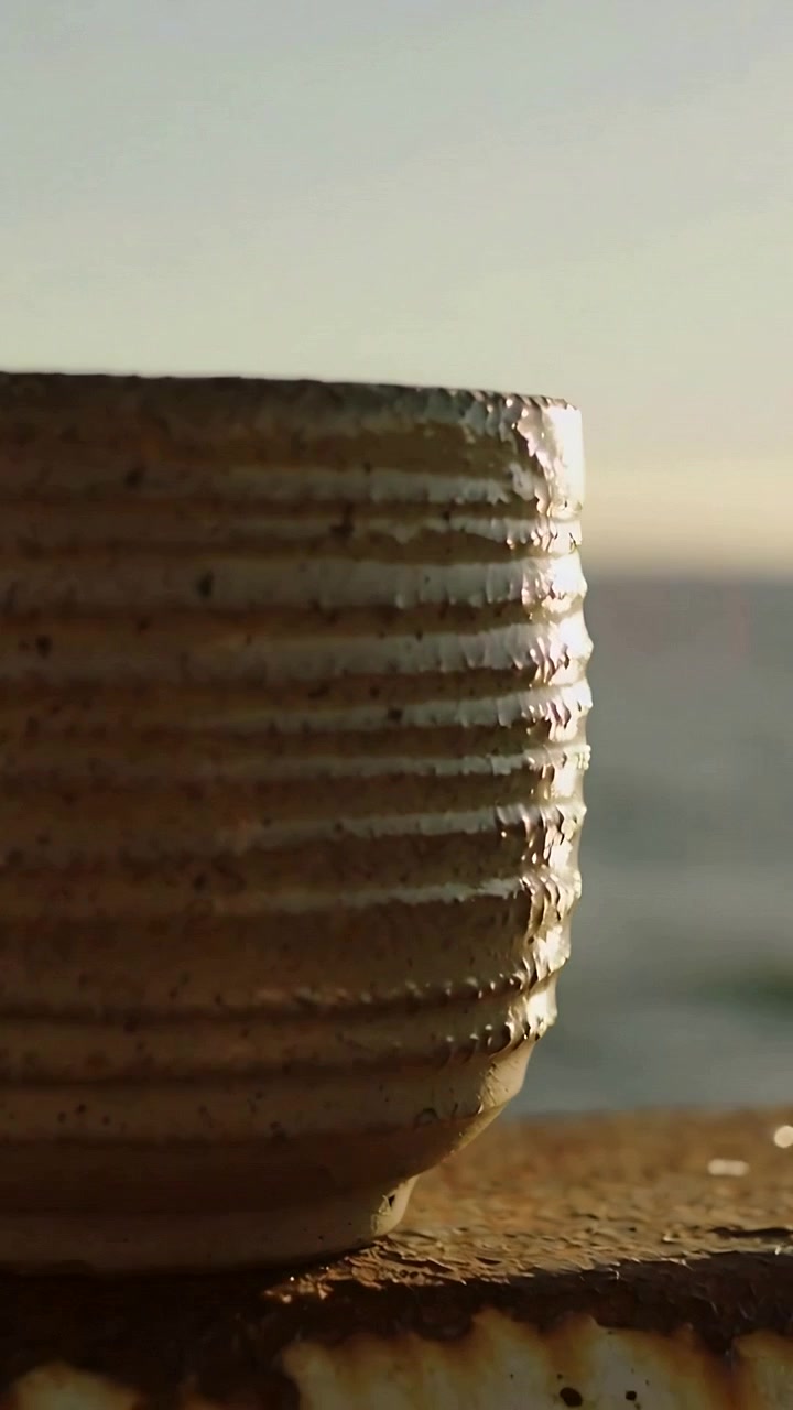 Vertical video: Shifting camera showing ribbed bowl on pier, sun striking droplets showing texture